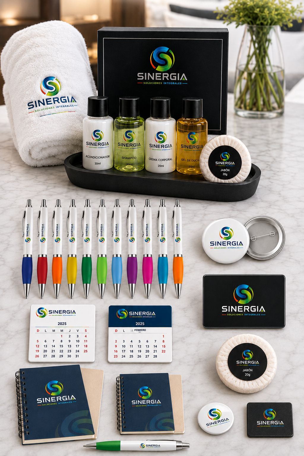 Set de merchandising personalizado con el logo de la empresa: amenities de hotelería, toalla bordada, lápices de colores, chapitas, imanes, calendarios magnéticos, libretas espiral y jabones de hotel